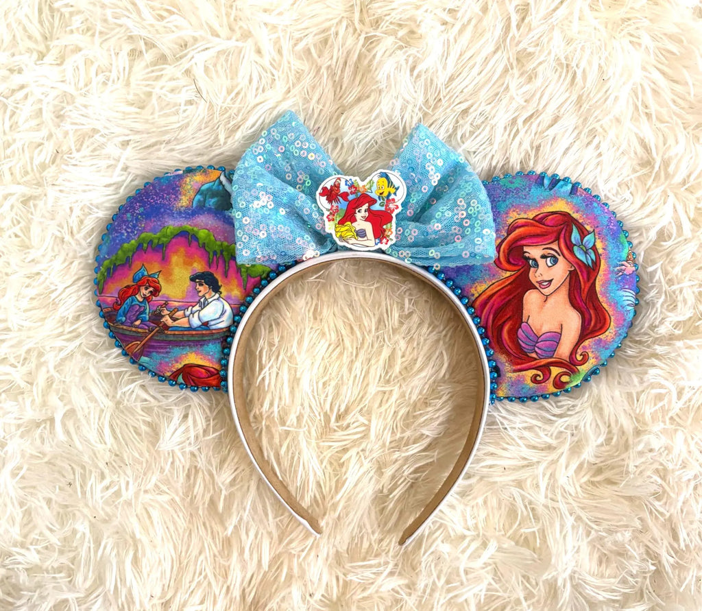 A Mermaid's Wish Boutique Mouse Ear Headband featuring enchanting ocean-inspired artwork, an aqua blue sequin bow, and handcrafted boutique detailing.