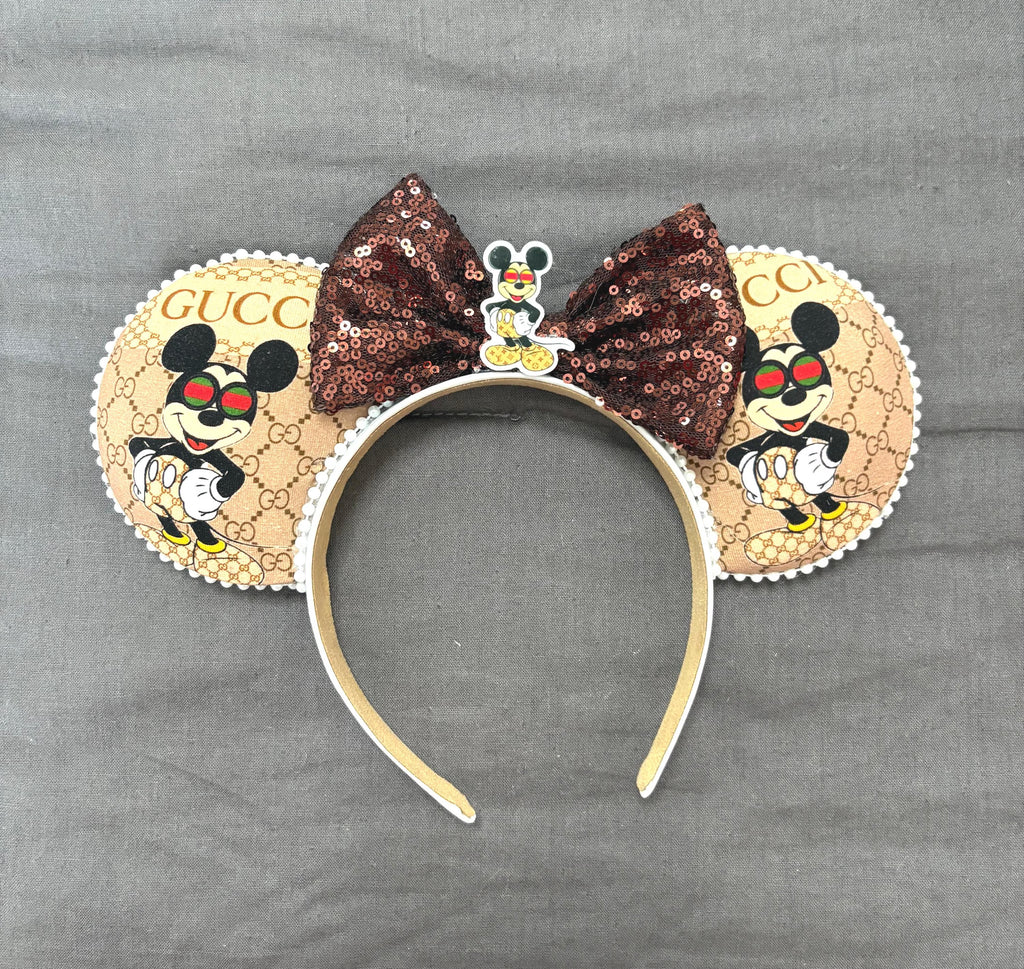 Handcrafted Espresso Chic boutique mouse ear headband featuring designer-inspired tan fashion print, rich espresso sequin bow, decorative resin centerpiece, and lightweight comfort-fit headband.