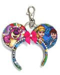 Toy Box Adventures Mini handcrafted mouse ear bag charm featuring colorful toy-inspired artwork with a coordinating decorative bow.