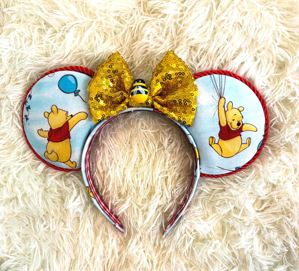 Handcrafted Honey Bear Boutique Mouse Ear Headband featuring honey-inspired fabric, a sparkling gold bow with bee accent, and comfortable all-day wear.

Description Intro