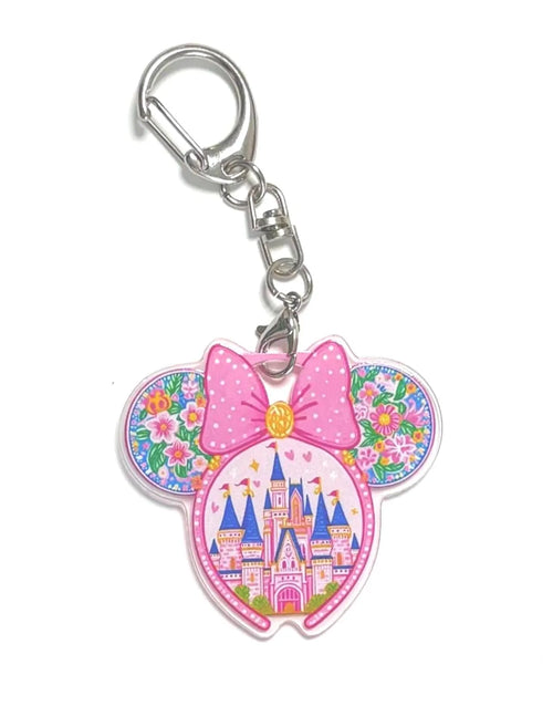 Castle in Bloom Pocket Charm featuring a pink bow, floral mouse ears, and a colorful storybook castle on a premium resin bag charm with lobster clasp