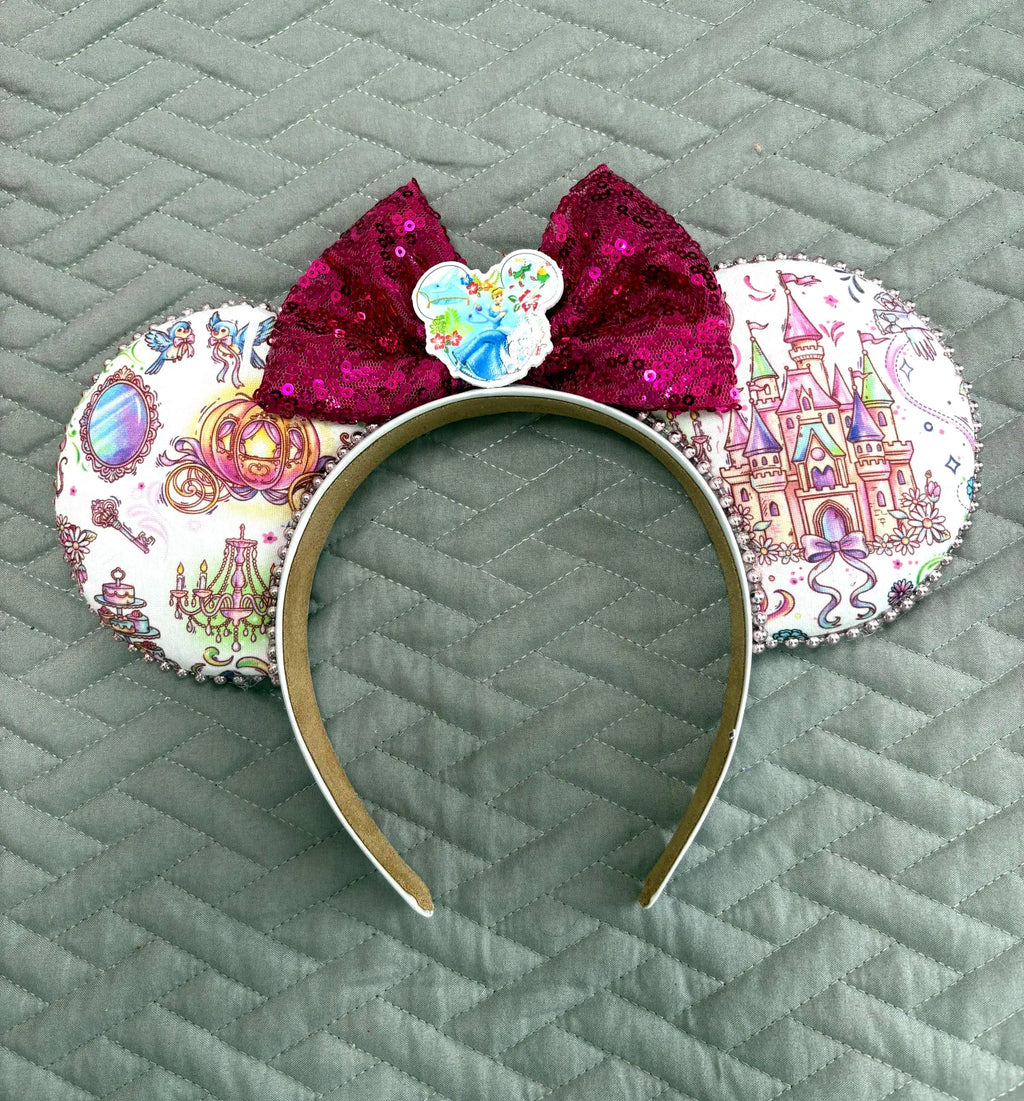 Enchanted Fairytale Boutique Mouse Ear Headband featuring fairytale castle, enchanted carriage, mirror and storybook-inspired artwork with a raspberry sequin bow.