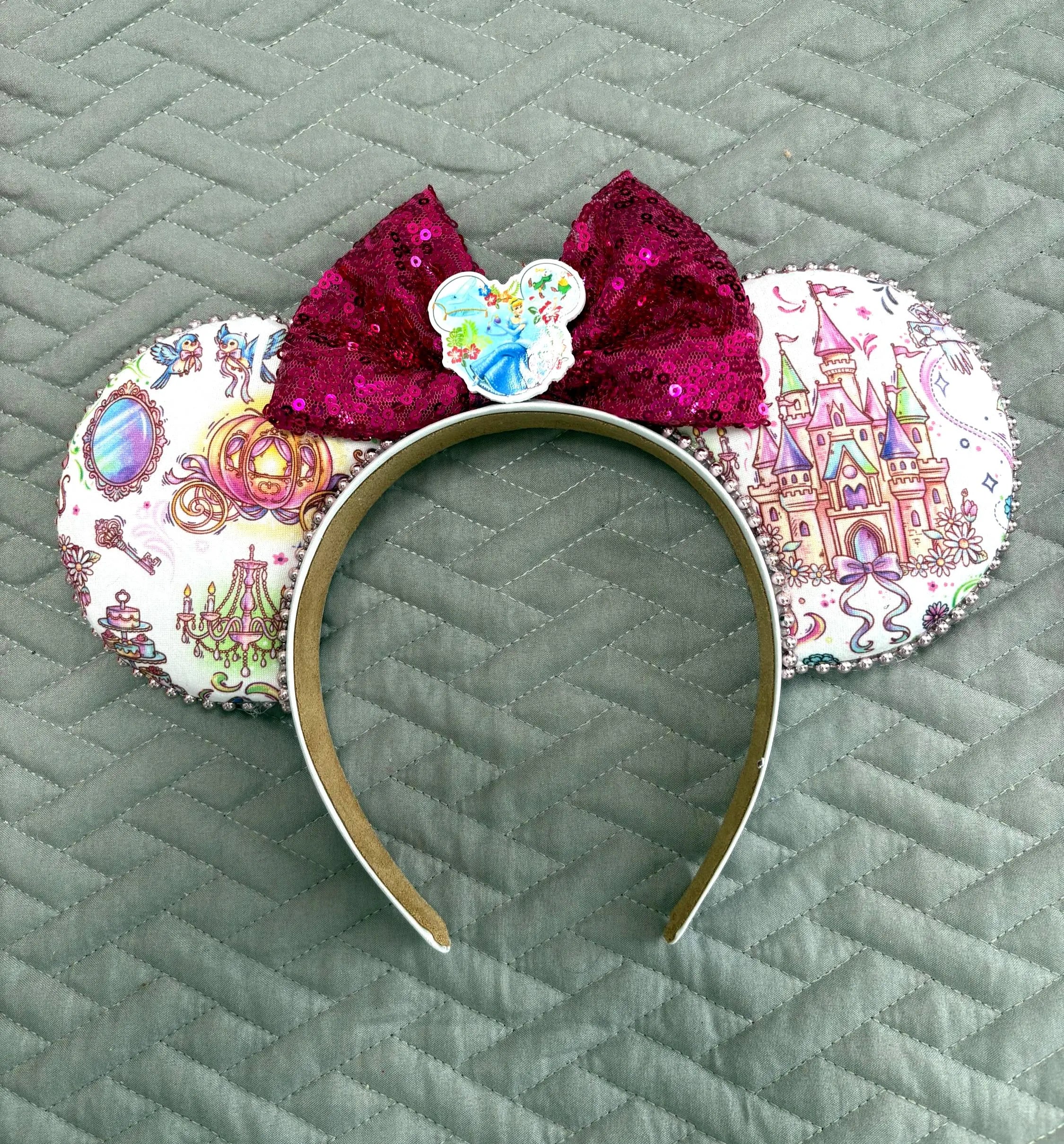 Enchanted Fairytale Boutique Mouse Ear Headband featuring fairytale castle, enchanted carriage, mirror and storybook-inspired artwork with a raspberry sequin bow.