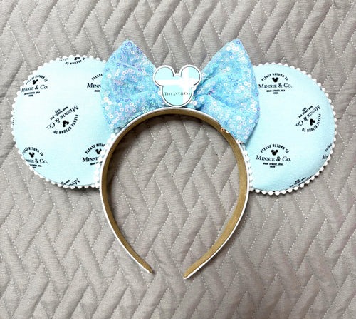 Handcrafted Blue Box Boutique mouse ear headband featuring designer-inspired robin's egg blue fabric, iridescent blue sequin bow, pearl trim, decorative mouse centerpiece, and lightweight comfort-fit headband.