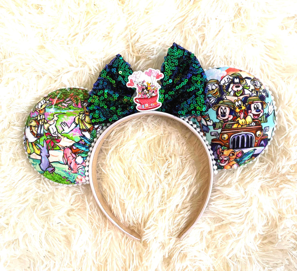 Jungle Expedition Boutique Mouse Ear Headband featuring a colorful safari-inspired character print, emerald green sequin bow, adventure-themed centerpiece, and handcrafted boutique styling by Pixie Park Co.