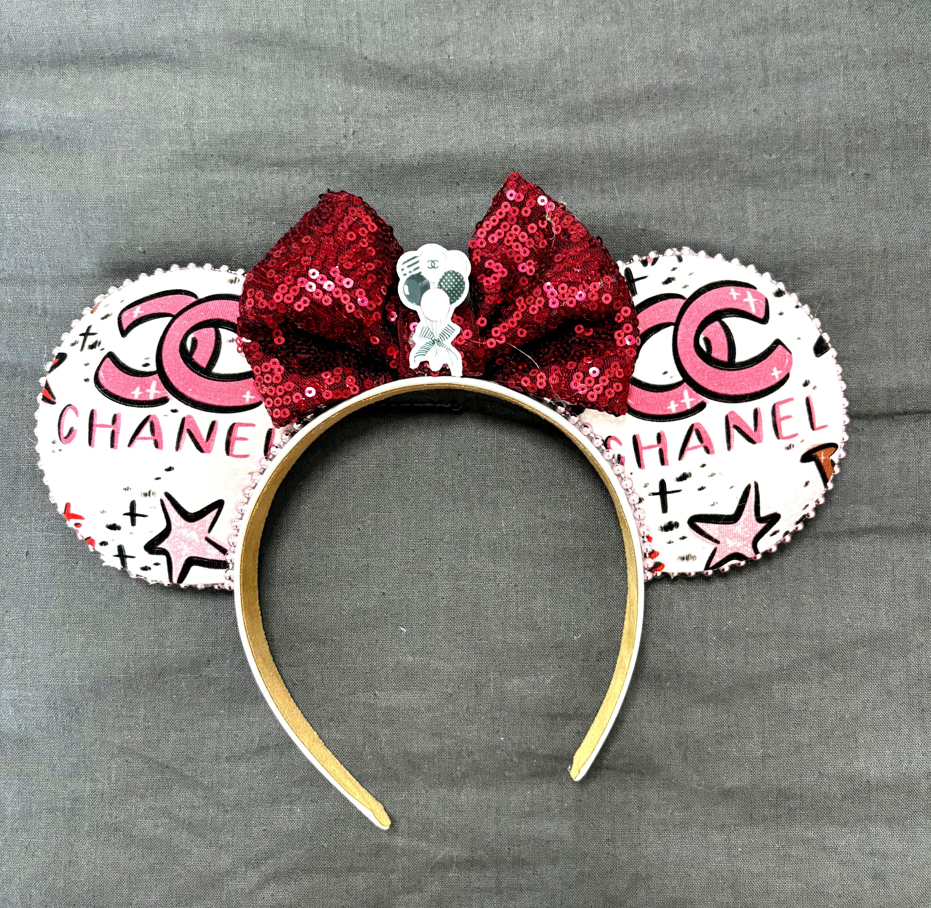 Handcrafted City Glam boutique mouse ear headband with designer-inspired fashion print, ruby-red sequin bow, decorative resin centerpiece, and lightweight comfort-fit headband.