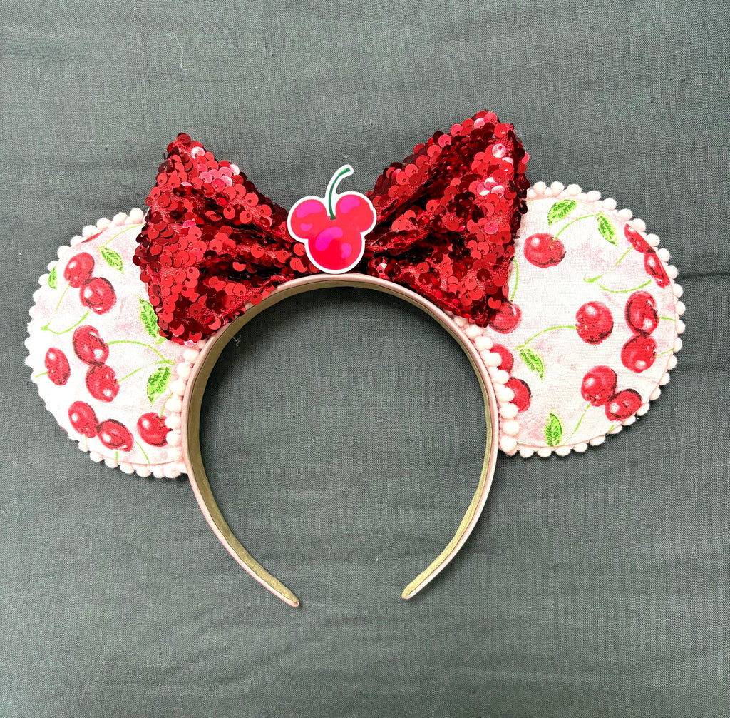 Handcrafted cherry-print boutique mouse ear headband with red sequined bow by Pixie Park Company.