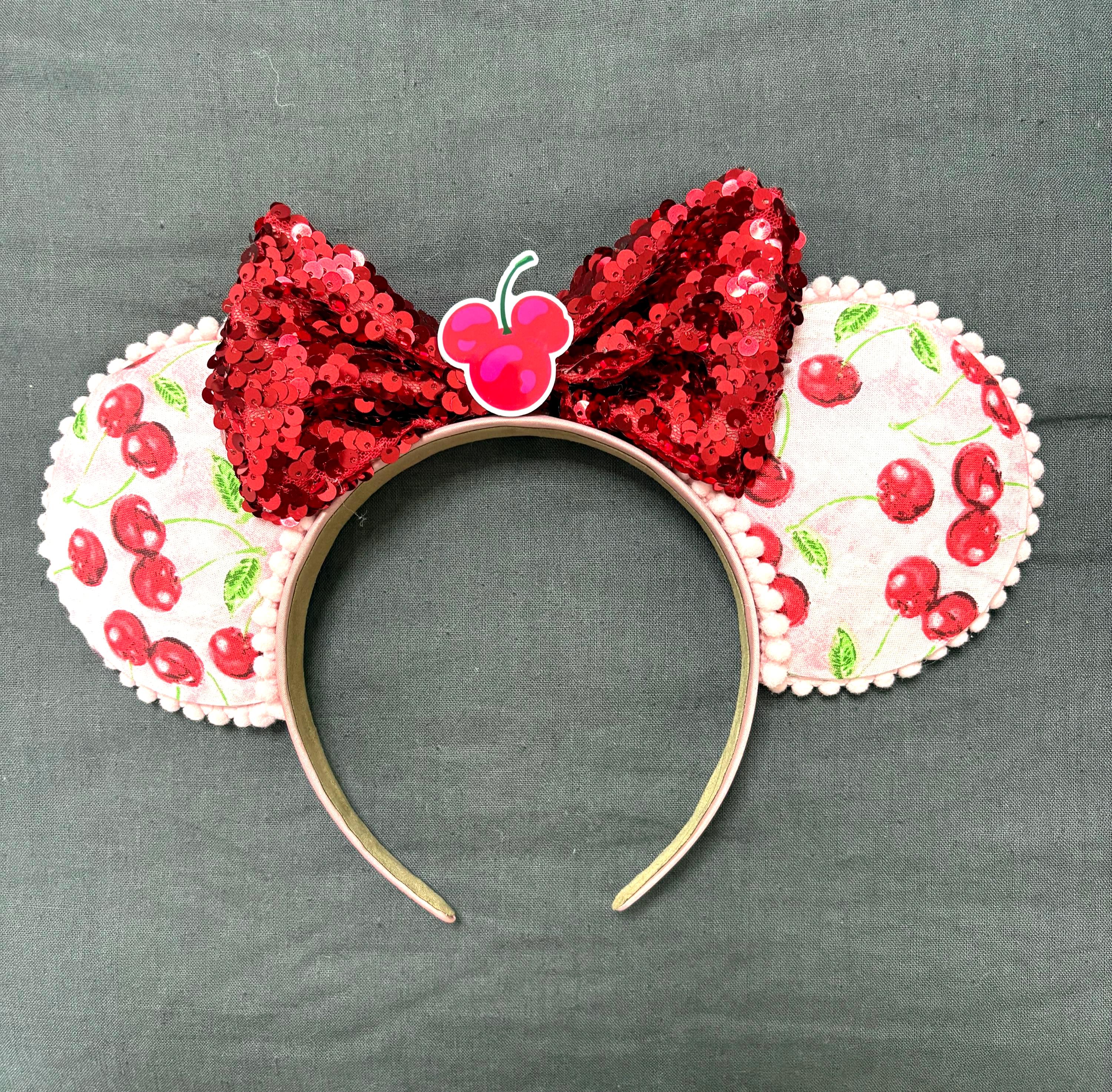 Handcrafted cherry-print boutique mouse ear headband with red sequined bow by Pixie Park Company.