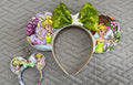 Handcrafted Pixie Dust Pixie Pair featuring a fairy-inspired mouse ear headband and coordinating Mini Magic Charm with pastel fairy artwork, shimmering green sequin bow, decorative pearl trim, and handcrafted boutique styling.