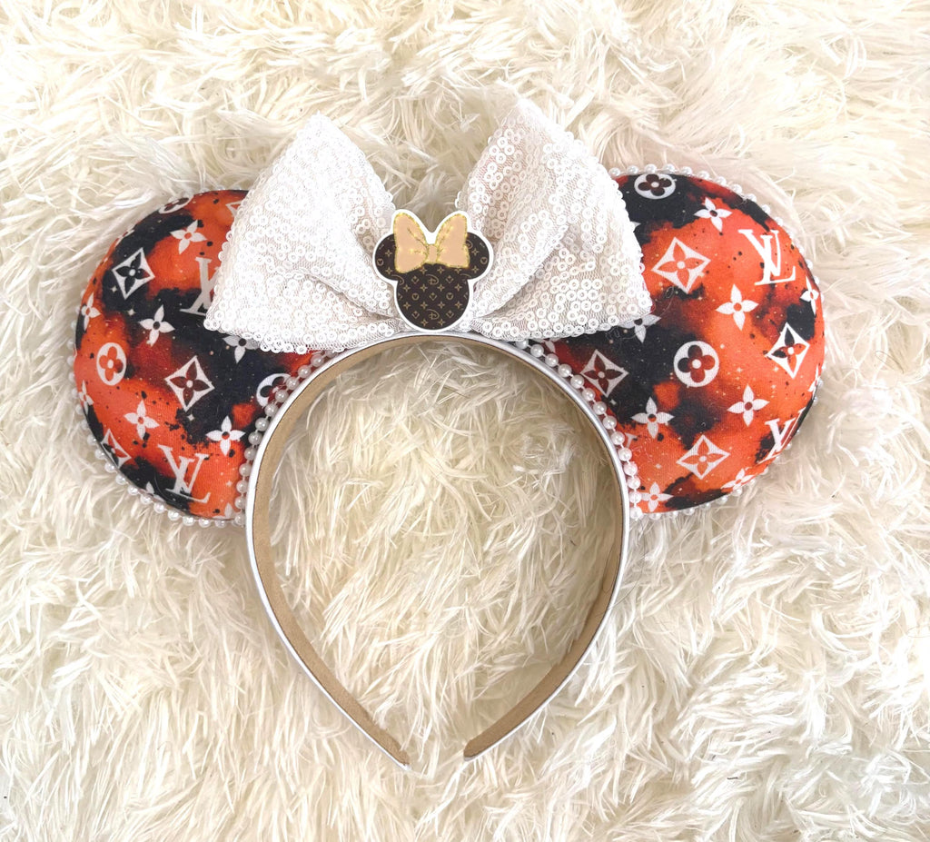 Handcrafted Ember Glow boutique mouse ear headband featuring designer-inspired orange, black, and white fabric, white sequin bow, pearl trim, decorative resin mouse silhouette centerpiece, and lightweight comfort-fit headband.