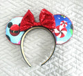 Holiday Magic handcrafted mouse ear headband featuring festive ornaments, peppermint candies, winter accents, and a sparkling red sequined bow from the Pixie Park Essentials Collection.