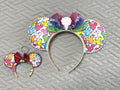 Handcrafted ColorPop Pixie Pair featuring a coordinating mouse ear headband and matching Mini Magic Charm with colorful mouse icon artwork, a rainbow ombré sequined bow, decorative pearl and rhinestone trim, and coordinated boutique styling for theme park outfits and everyday accessories.