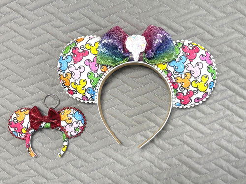 Handcrafted ColorPop Pixie Pair featuring a coordinating mouse ear headband and matching Mini Magic Charm with colorful mouse icon artwork, a rainbow ombré sequined bow, decorative pearl and rhinestone trim, and coordinated boutique styling for theme park outfits and everyday accessories.