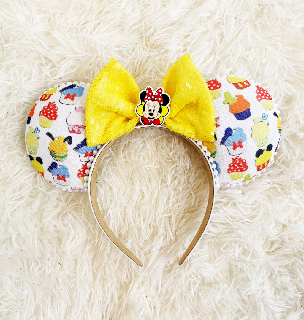 Sweet Treats Boutique Mouse Ear Headband from the Pixie Park Essentials Collection featuring colorful dessert-inspired artwork, a bright yellow sequin bow, decorative centerpiece, and handcrafted lightweight comfort-fit design.