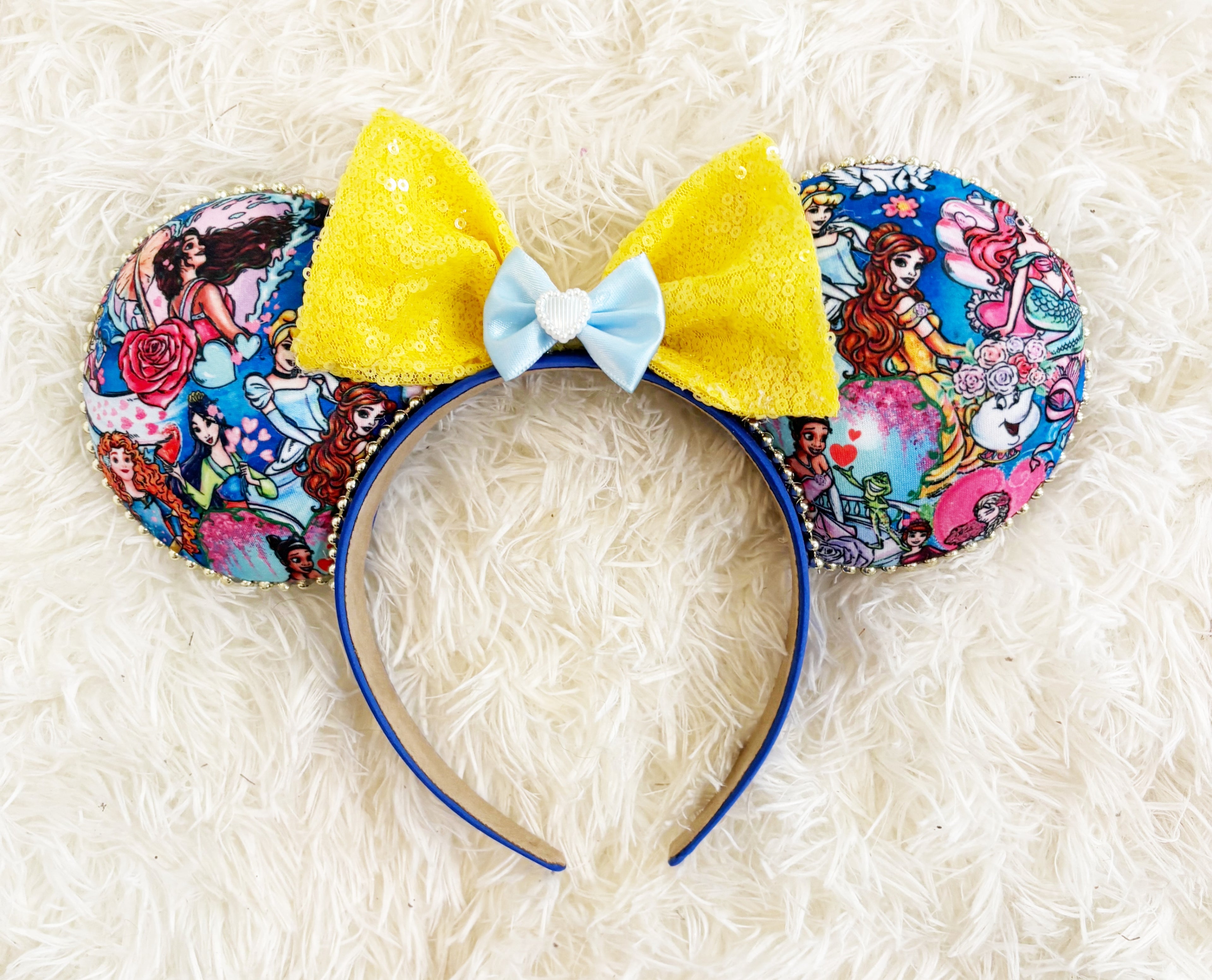 Princess Parade Boutique Mouse Ear Headband featuring princess-inspired artwork, sunshine yellow sequin bow with blue satin ribbon accent, handcrafted boutique styling, and comfort-fit headband by Pixie Park Company.