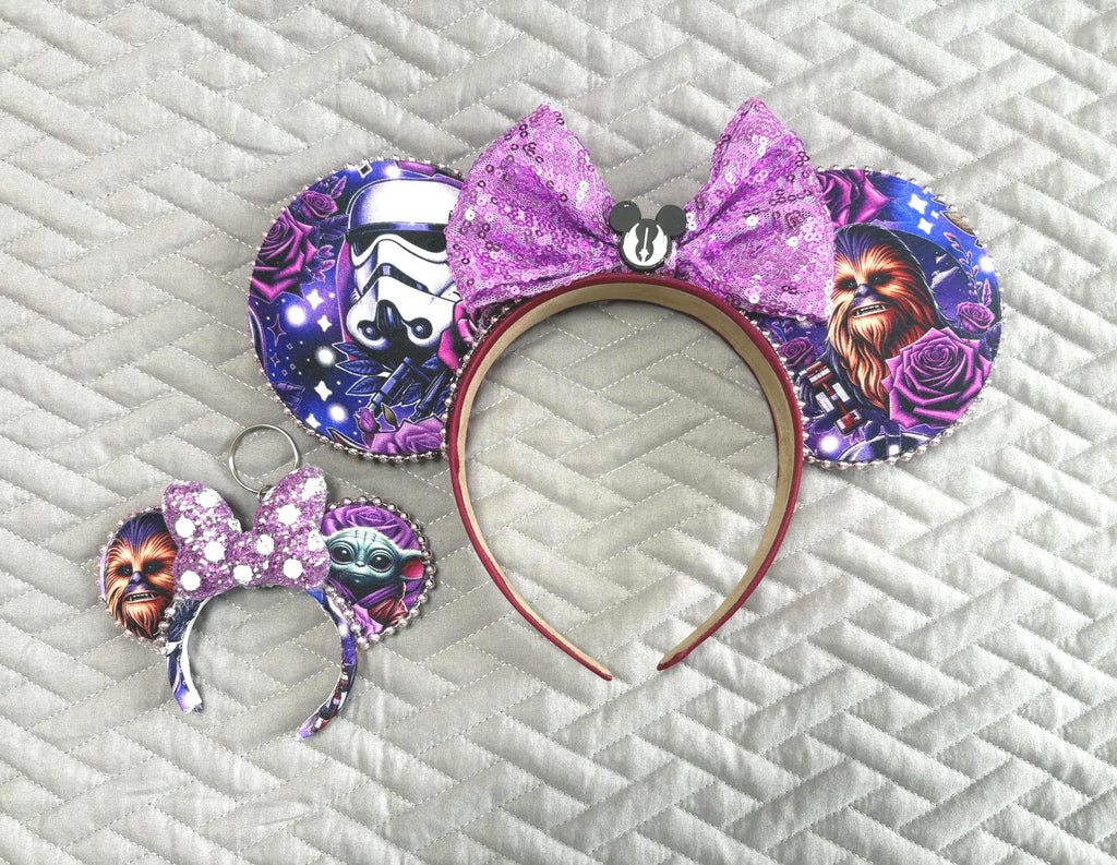 Handcrafted Galactic Adventure Pixie Pair featuring a coordinating mouse ear headband and matching Mini Magic Charm with galactic-inspired character artwork, sparkling purple sequined bows, decorative rhinestone trim, and coordinated boutique styling for theme park outfits and everyday accessories.