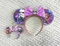 Handcrafted Galactic Adventure Pixie Pair featuring a coordinating mouse ear headband and matching Mini Magic Charm with galactic-inspired character artwork, sparkling purple sequined bows, decorative rhinestone trim, and coordinated boutique styling for theme park outfits and everyday accessories.
