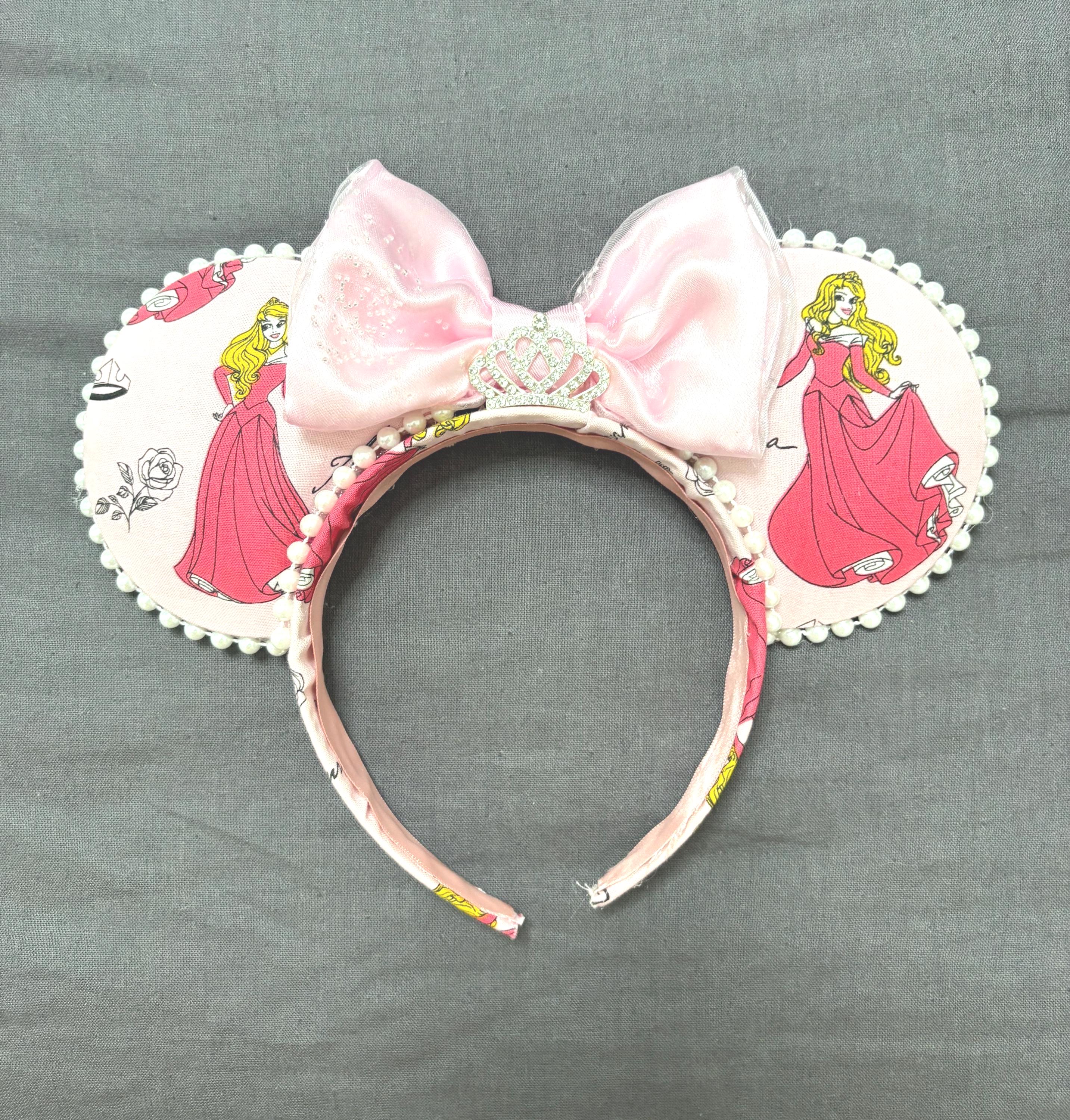 Pink Princess Boutique Mouse Ear Headband from the Pixie Park Essentials Collection featuring classic storybook-inspired artwork, a soft pink satin bow with tiara accent, handcrafted styling, and lightweight comfort-fit design.
