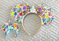 Handcrafted Park Celebration Pixie Pair featuring a matching mouse ear headband and coordinating Mini Magic Charm with colorful park-inspired artwork, classic attractions, favorite characters, decorative castle centerpiece, boutique bow, beaded trim, and handcrafted boutique styling.