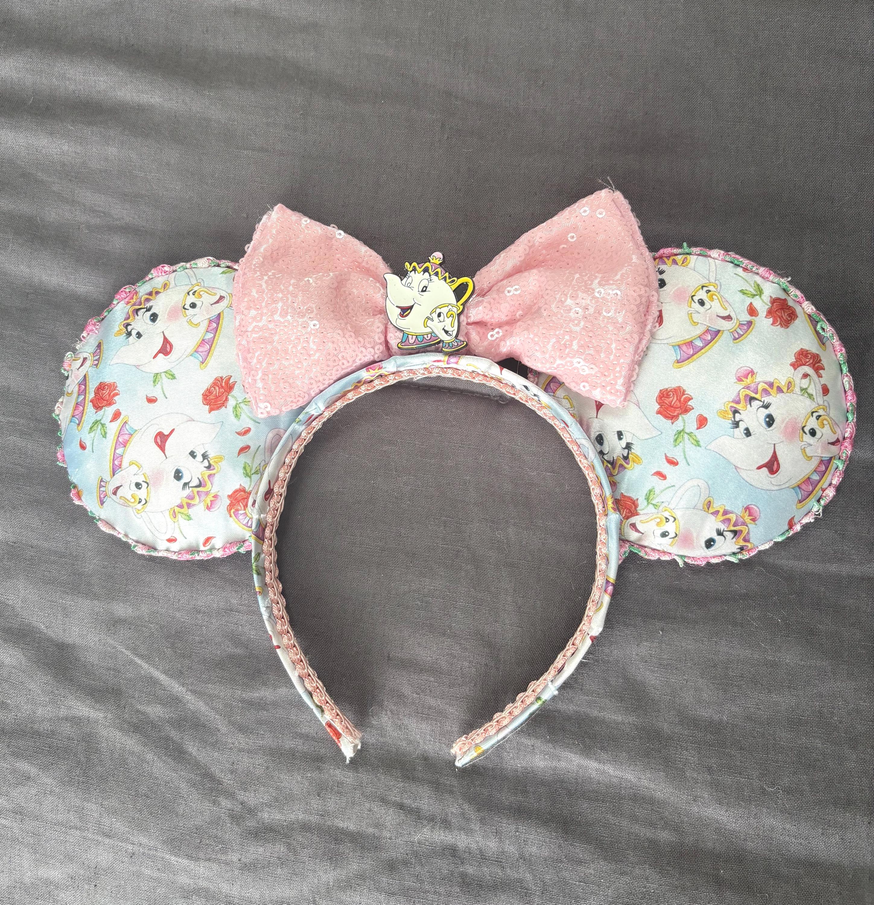 Enchanted Tea Party Boutique Mouse Ear Headband from the Pixie Park Essentials Collection featuring handcrafted mouse ears with teacup-inspired artwork, a soft pink sequin bow, decorative tea party centerpiece, and lightweight comfort-fit design.