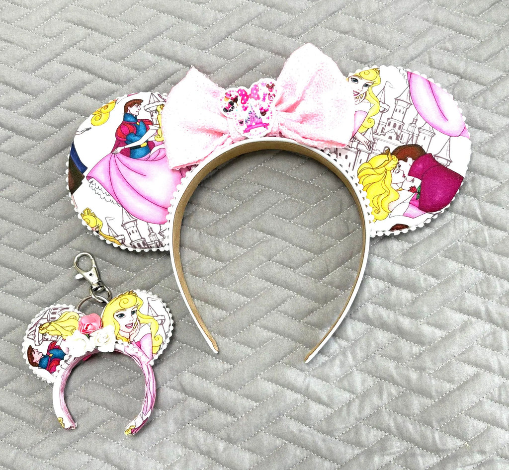 Handcrafted Once Upon a Dream Pixie Pair featuring a princess-inspired mouse ear headband and coordinating Mini Magic Charm with elegant fairytale artwork, castle scenes, a white sequined bow with sparkling castle centerpiece, floral accents, decorative beaded trim, and boutique handcrafted styling.
