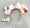 Handcrafted Once Upon a Dream Pixie Pair featuring a princess-inspired mouse ear headband and coordinating Mini Magic Charm with elegant fairytale artwork, castle scenes, a white sequined bow with sparkling castle centerpiece, floral accents, decorative beaded trim, and boutique handcrafted styling.