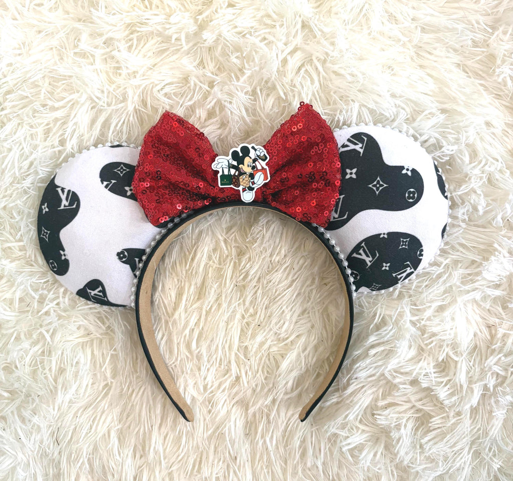 Wild Luxe boutique mouse ear headband featuring a black-and-white fashion-inspired print, ruby red sequin bow, shopping-themed mouse centerpiece, and pearl trim.