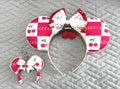 Handcrafted Cherry Belle Pixie Pair featuring a cherry-inspired mouse ear headband with ruby-red sequin bow, white lace overlay, cherry embellishments, decorative pearl-style trim, and a matching Mini Magic Charm with coordinating cherry artwork and handcrafted ribbon accents.