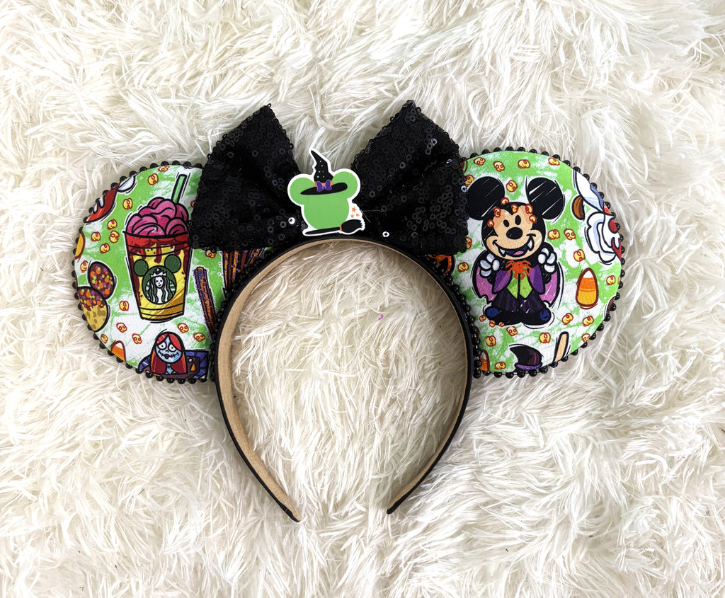 Handcrafted Halloween mouse ear headband featuring playful vampire-inspired artwork, festive treats, candy corn accents, and a sparkling black sequin bow.