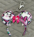 Pixie Park Company Couture Cats Mini Magic Charm featuring Paris-inspired pastel kitten artwork, a shimmering lavender boutique bow, decorative white beaded trim, and a coordinating keyring attachment.
