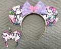 Pixie Park Company Couture Cats Pixie Pair featuring a coordinated Signature mouse ear headband and matching Mini Magic Charm with Paris-inspired pastel kitten artwork, a shimmering lavender sequin bow, decorative white beaded trim, and handcrafted boutique styling.