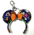 Pixie Park Company Pumpkin Parade Mini Magic Charm featuring festive Halloween-inspired artwork, a bright orange boutique bow, decorative black beaded trim, a miniature jack-o'-lantern centerpiece, and a silver keyring with lobster clasp attachment.