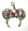 Pixie Park Company Picnic Pals Mini Magic Charm featuring playful picnic-inspired artwork, a coordinating boutique bow, decorative beaded trim, and a silver keyring with lobster clasp attachment.