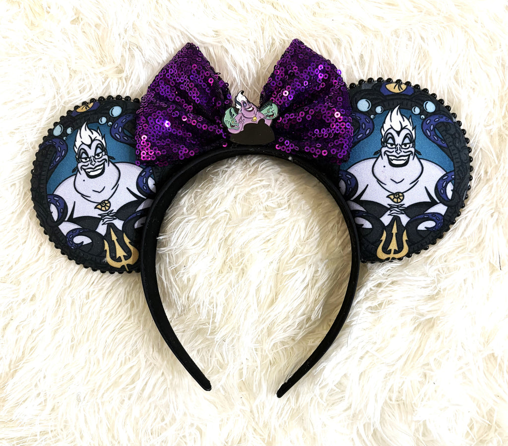 Handcrafted villain-inspired mouse ear headband featuring sea witch artwork, a shimmering purple sequined bow, black beaded trim, and a decorative centerpiece by Pixie Park Co.