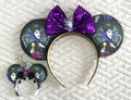 Handcrafted Mistress of Magic Pixie Pair featuring coordinated villain-inspired accessories with rich purple boutique styling, designed for backpacks, purses, park bags, and Halloween-themed magical adventures.