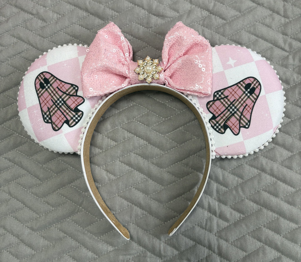 Handcrafted Pink Haunting Signature mouse ear headband featuring ghost-inspired blush plaid fabric, a pink sequined bow, pearl trim, jeweled centerpiece, and boutique craftsmanship for Halloween and autumn park adventures.