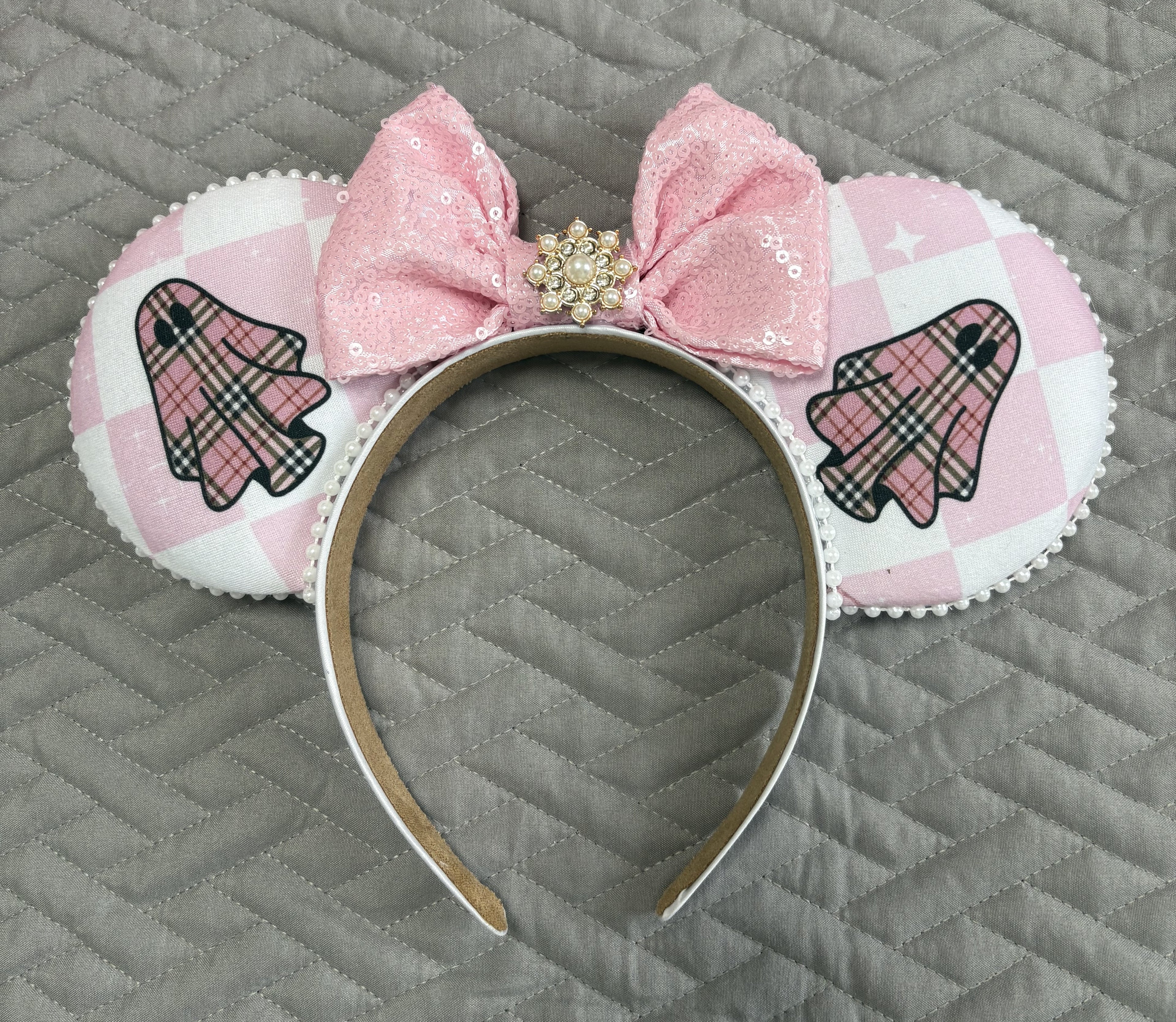 Handcrafted Pink Haunting Signature mouse ear headband featuring ghost-inspired blush plaid fabric, a pink sequined bow, pearl trim, jeweled centerpiece, and boutique craftsmanship for Halloween and autumn park adventures.