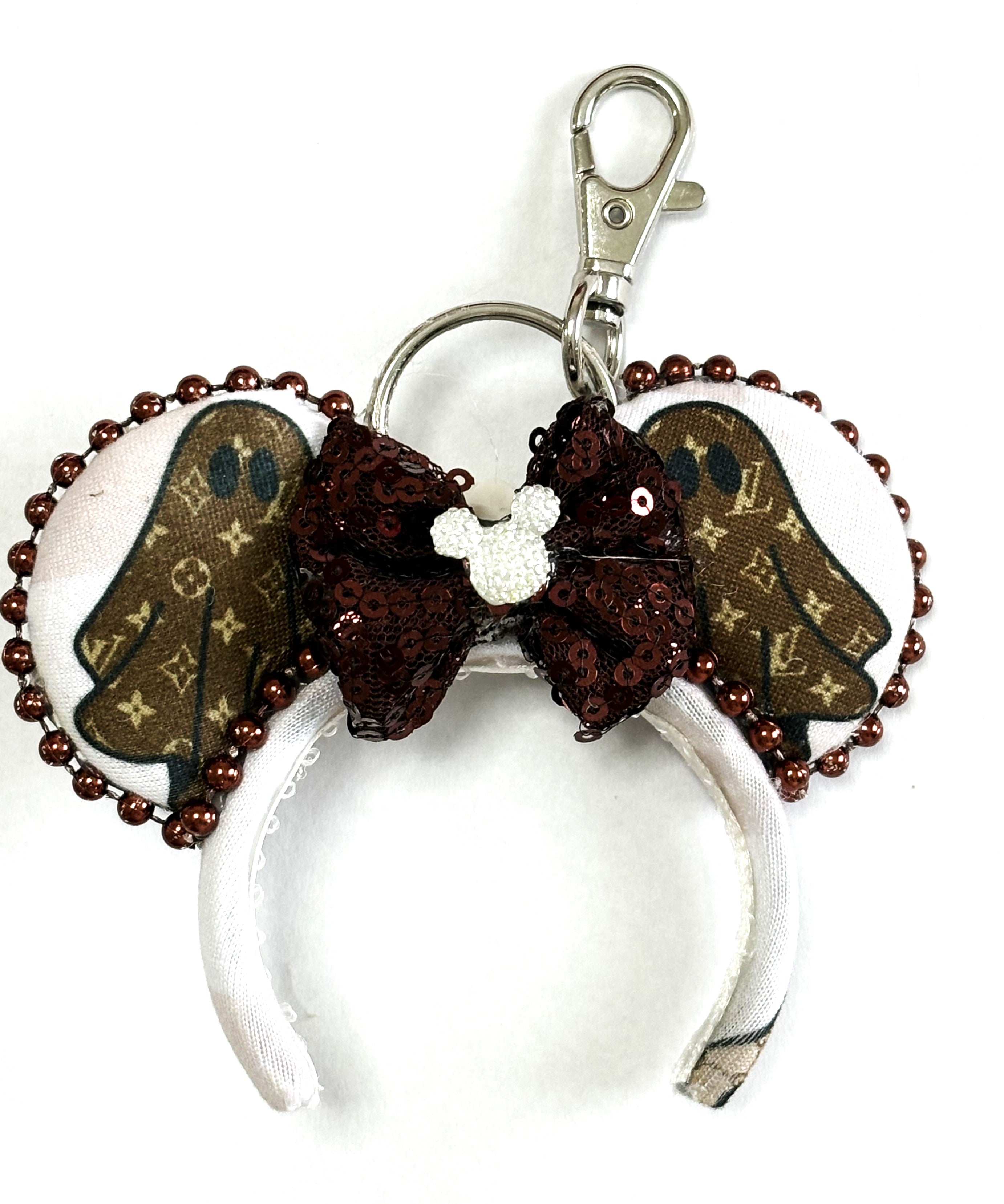 Handcrafted Haunted Couture Mini Magic Charm featuring luxury-inspired ghost-themed fabric, elegant neutral tones, boutique detailing, and a secure clasp for backpacks, purses, keychains, and Halloween park adventures.