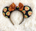 Handcrafted Poison Apple Brew Halloween mouse ear headband with bright poison-apple-inspired print, sparkling orange bow, black beaded trim and colorful bubbling cauldron centerpiece.