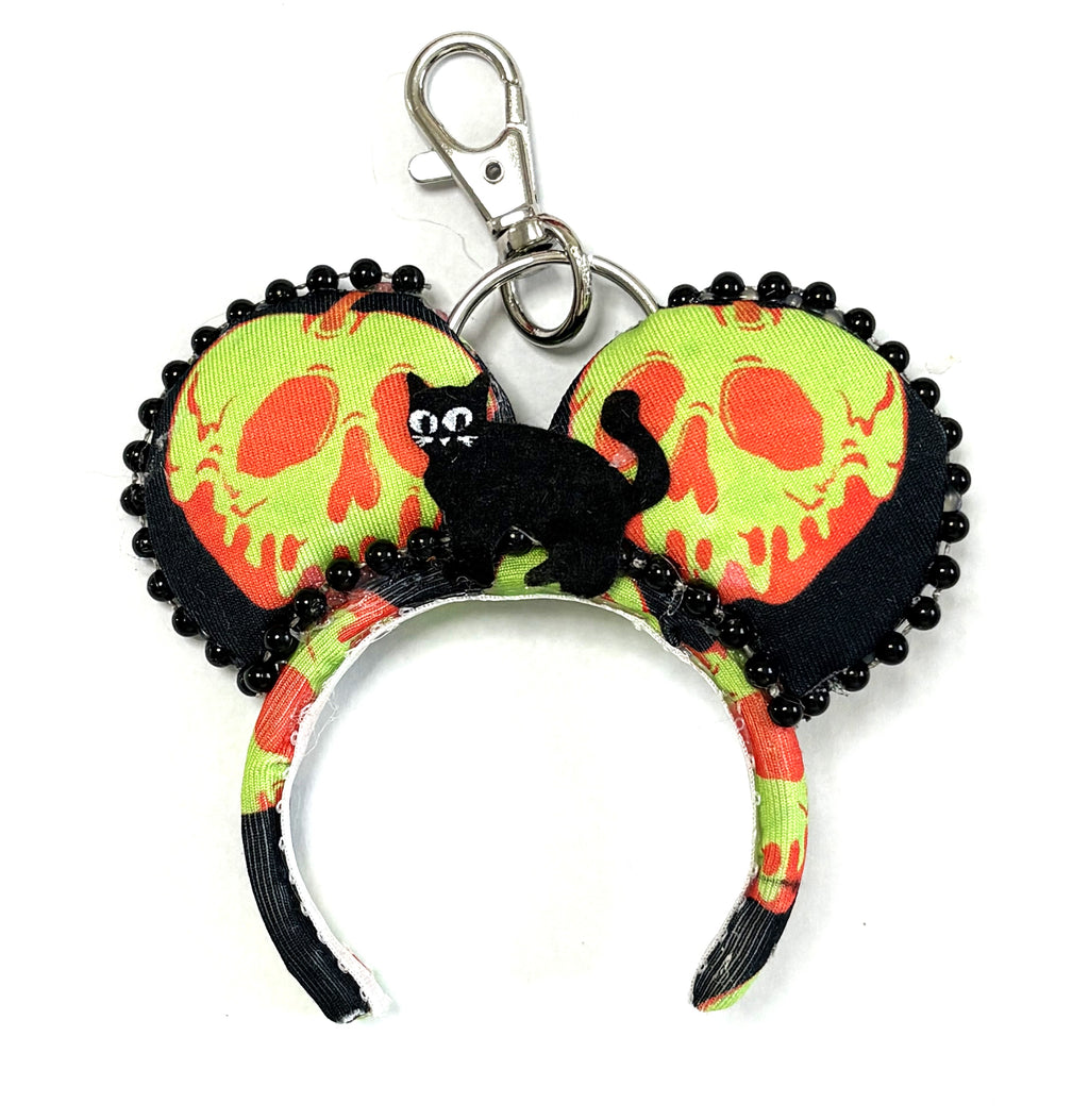 Poison Apple Brew is a handcrafted mini ear charm with black fabric, bright poison-apple-inspired print, spooky accents, lobster clasp and split ring.