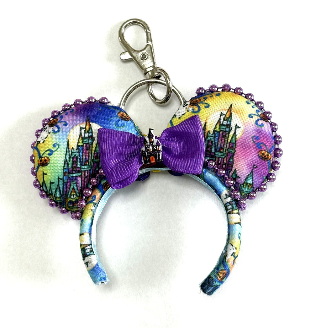 Midnight Kingdom handcrafted mini ear charm featuring colorful Halloween castle fabric, pumpkins, ghosts, purple bow, beaded trim, lobster clasp and split ring.