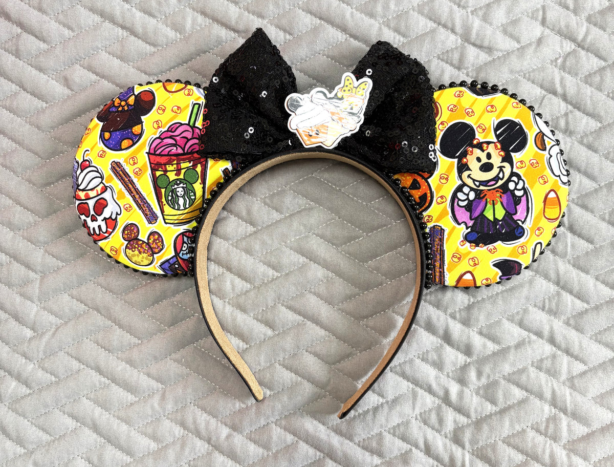 Spooky Treats  handcrafted Halloween mouse ear headband featuring colorful candy, pumpkins and seasonal treat imagery with a sparkling black sequin bow and black beaded trim.