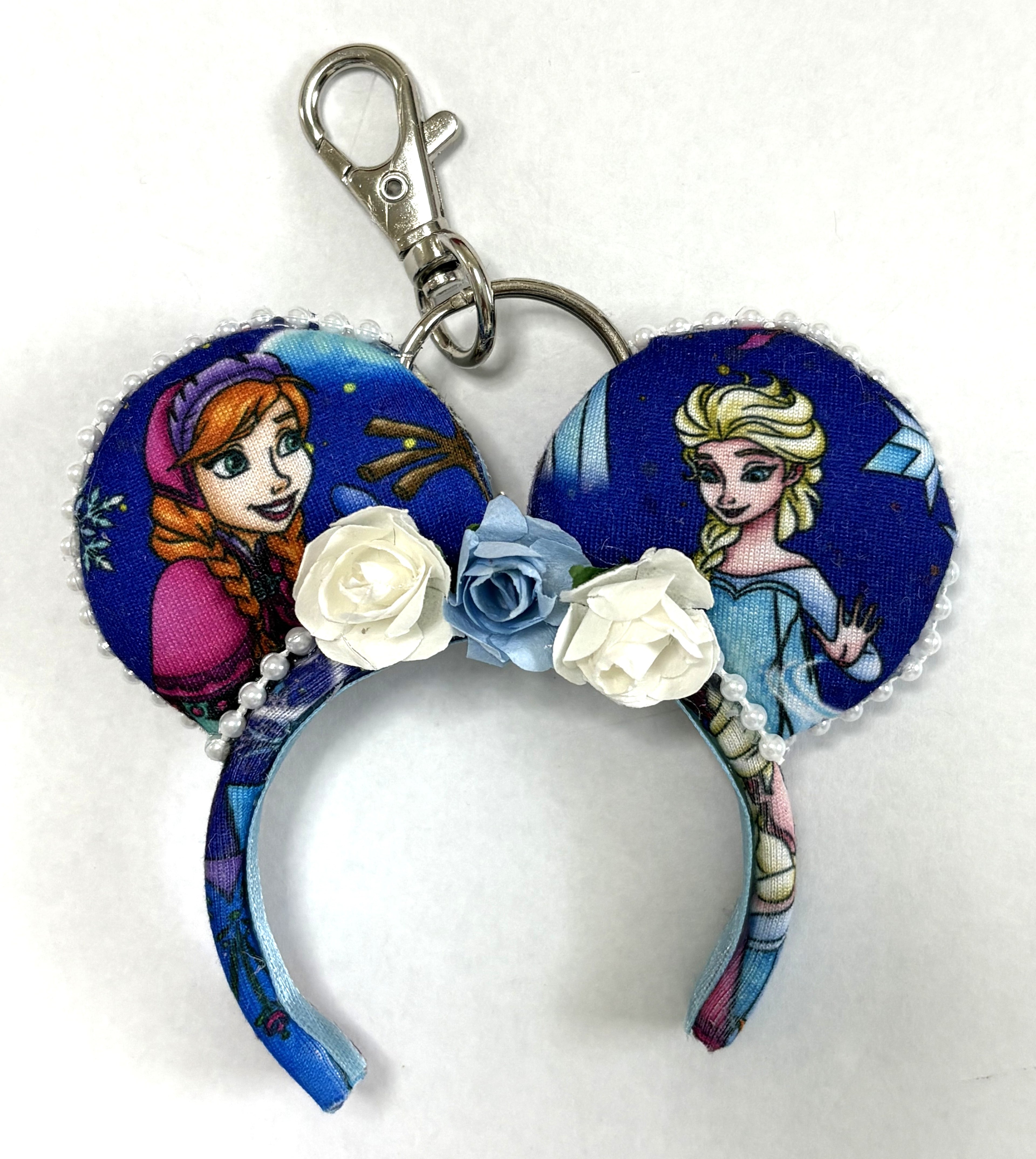 Sisters of Winter handcrafted mini ear charm featuring two winter-princess-inspired sisters, blue and white floral accents, beaded trim, lobster clasp and split ring.