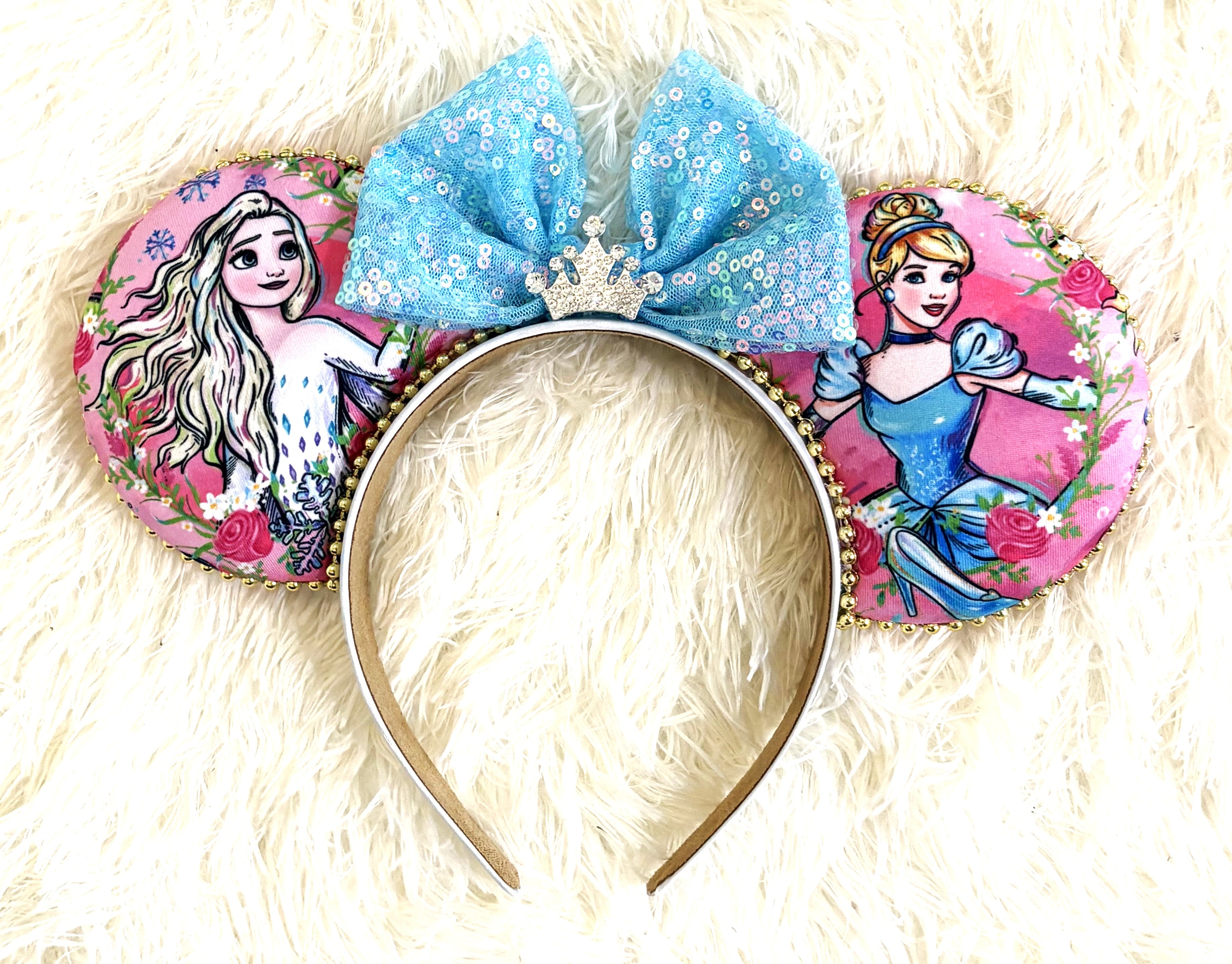 Handcrafted Enchanted Ice & Glass Princess Duo mouse ear headband featuring two princess-inspired designs, an icy-blue sequined bow, crystal crown centerpiece, pink floral fabric, and boutique beaded trim by Pixie Park Co.