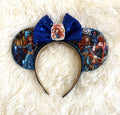 Handcrafted Highland Destiny princess-inspired mouse ear headband with Scottish storybook scenes, blue beaded trim, royal-blue sequin bow and princess centerpiece.