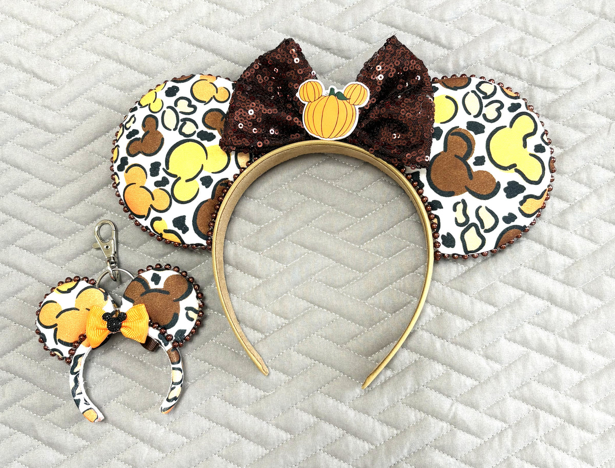 Handcrafted Harvest Mouse Magic Pixie Pair featuring autumn mouse-patterned Signature ears with a chocolate-brown sequin bow and pumpkin centerpiece, plus a matching miniature ear bag charm with a golden-orange bow.
