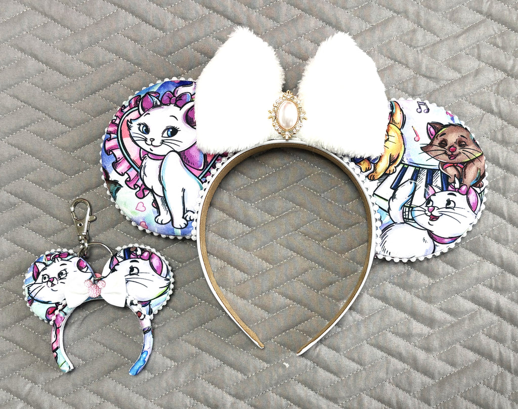 Parisian Kitty Pixie Pair with handcrafted kitten-print mouse ear headband and matching mini bag charm, pearl trim, plush white bow and jeweled accents.