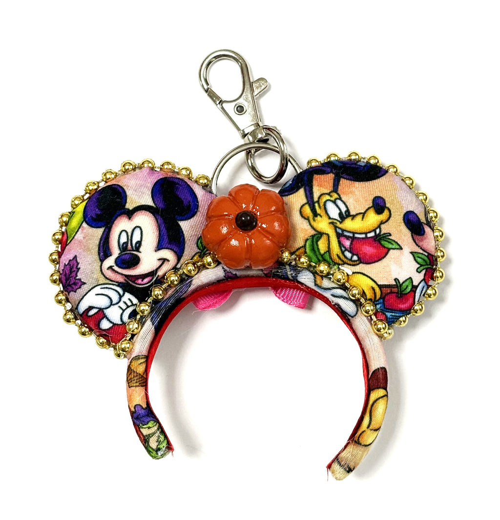 Handcrafted Autumn Friends mini mouse ear bag charm with colorful fall scenes, gold beaded trim, orange bow, pumpkin centerpiece and metal clasp.