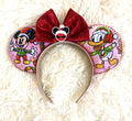 Jolly Holiday Friends handcrafted mouse ear headband featuring pink Christmas character fabric, ruby-red beaded trim, oversized red velvet bow, and Santa-inspired centerpiece.