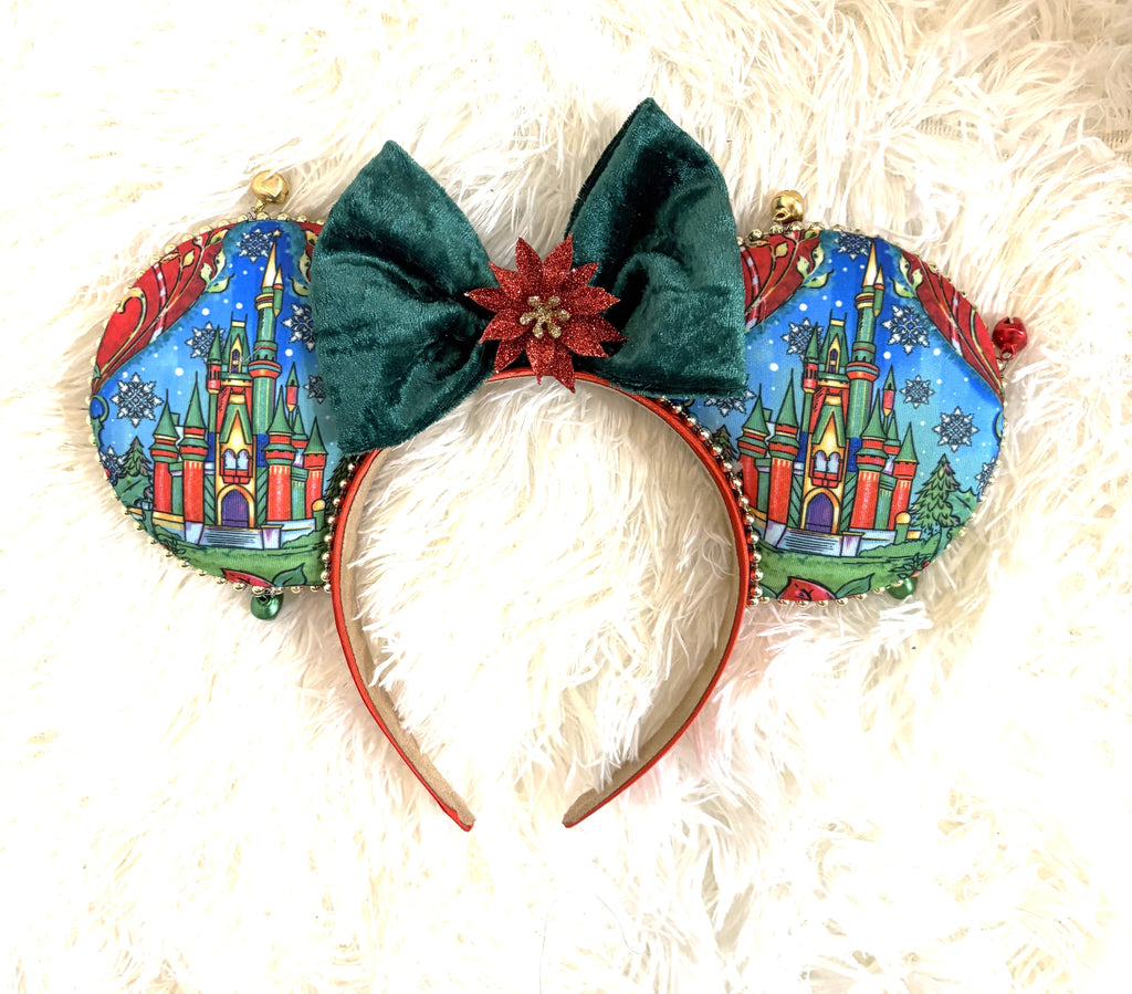 Christmas Castle Wishes handmade mouse ear headband featuring colorful holiday castle fabric, emerald-green velvet bow, glittering red poinsettia, gold bead trim, and green jingle bells.